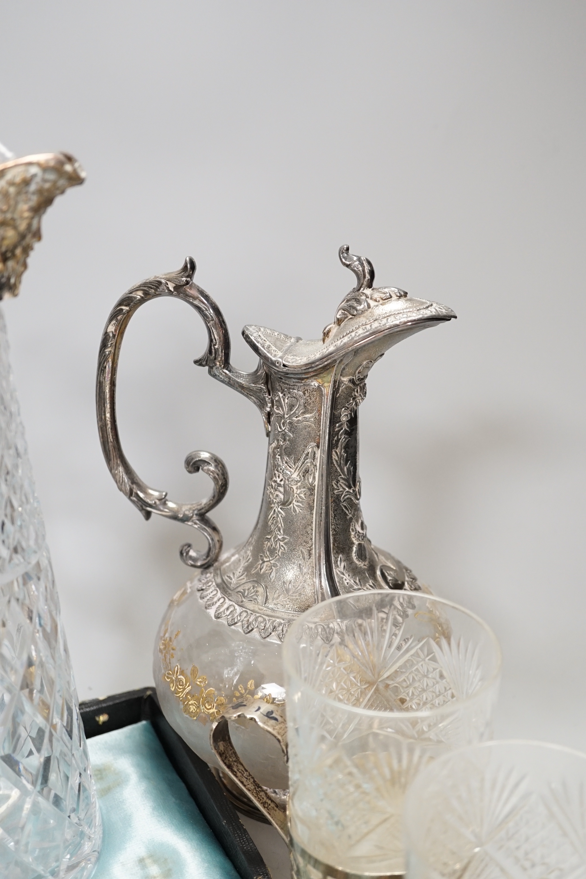 Two claret jugs, one with gilt decoration, four silver plated cup holders with glass liners and silver plated fish servers, the largest 32cm high